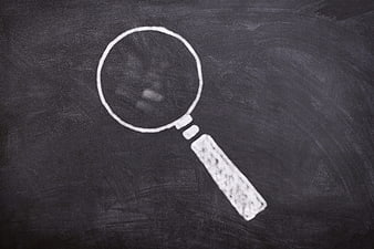 White Chalk Magnifying Glass Drawing On Dark Blackboard Surface