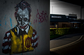 Joker Graffiti on Concrete Wall with McDonald's in Background