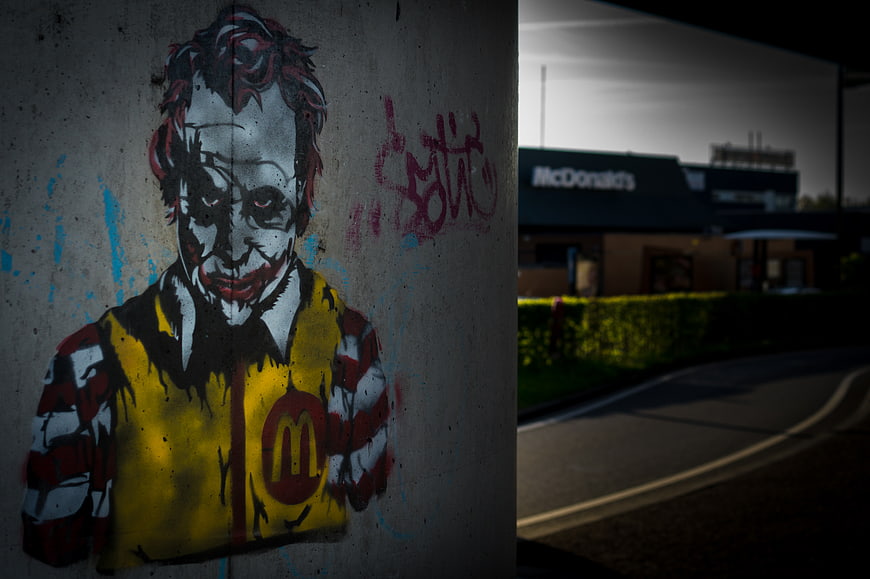 Joker Graffiti on Concrete Wall with McDonald's in Background