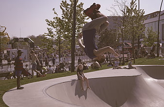 Skateboarder performing aerial flip trick at outdoor skate park
