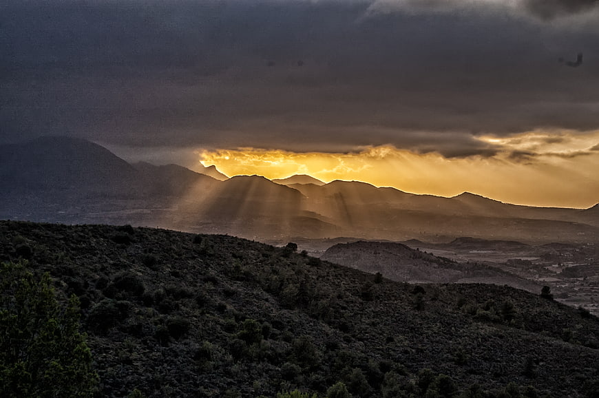 Dramatic sunset with sun rays over mountain landscape