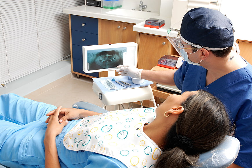 Dentist showing dental X-ray to female patient in clinic