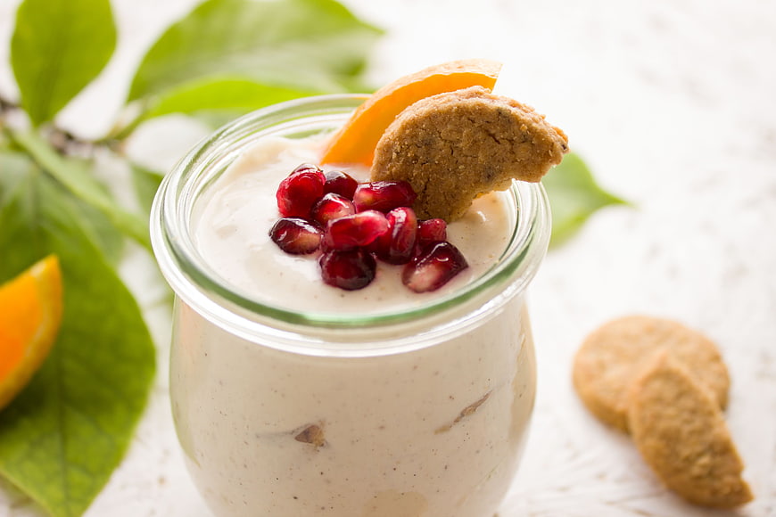 Healthy breakfast yogurt parfait with pomegranate seeds, orange slice, and cookie