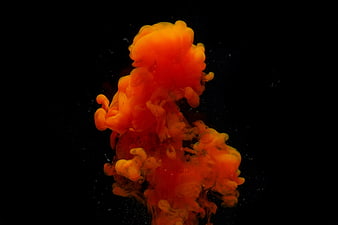 Vibrant orange ink swirling in dark water abstract background
