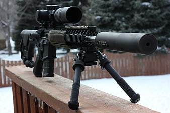 Tactical rifle with suppressor on snowy deck railing