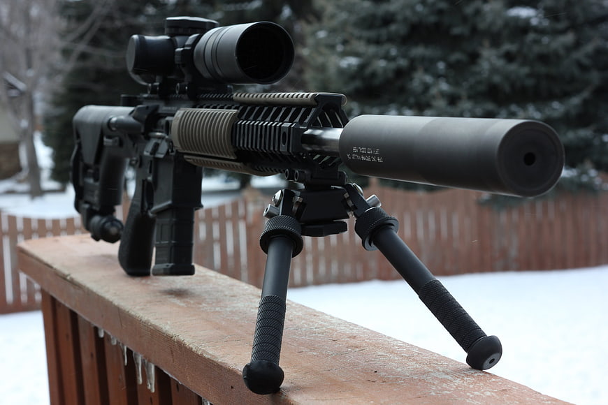 Tactical rifle with suppressor on snowy deck railing