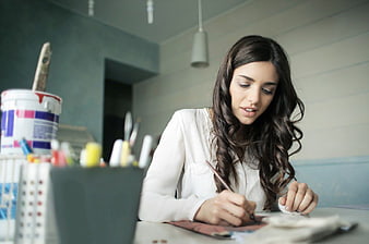 Young Woman Painting at Desk in Art Studio