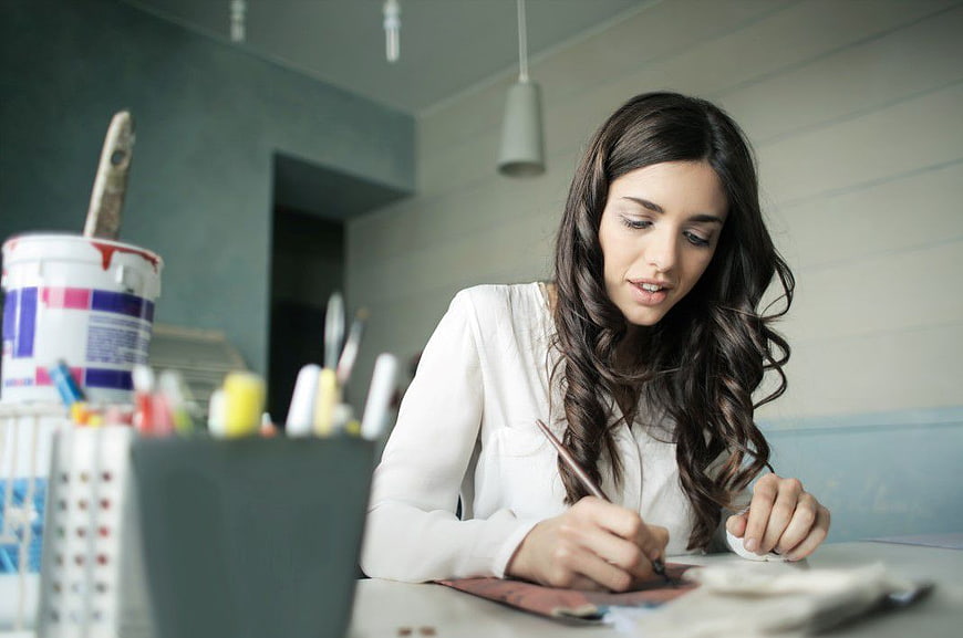 Young Woman Painting at Desk in Art Studio