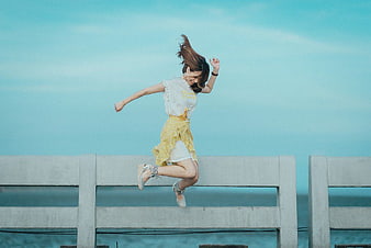 Happy Woman Jumping on Pier Against Blue Sky