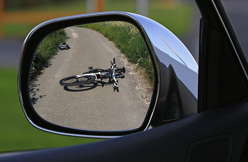 Bicycle lying on road reflected in car side mirror