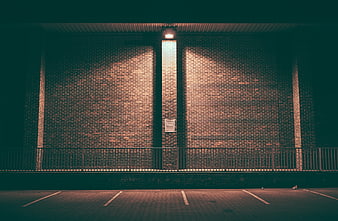 Empty parking lot with brick wall and railing at night