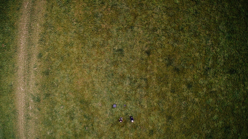 Aerial view of two people relaxing on a green meadow