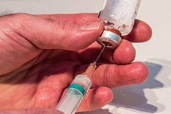 Close-up of hand drawing medicine from vial into syringe