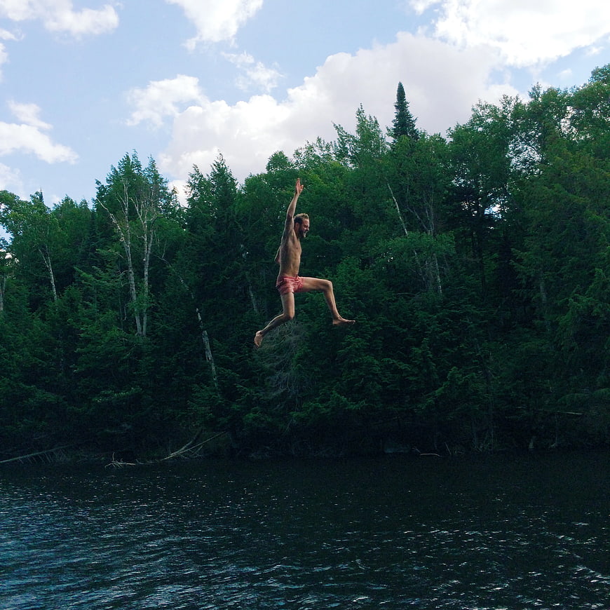 Man Jumping into Lake with Forest Background