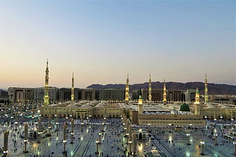 Al-Masjid an-Nabawi Mosque at Dusk with Minarets and Crowd