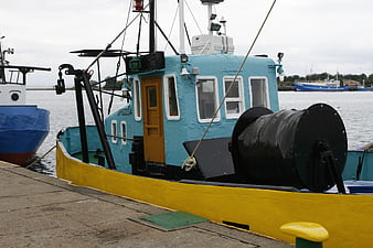Colorful blue and yellow fishing boat docked at harbor