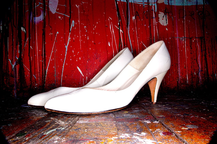 White high heels on rustic red painted wooden background