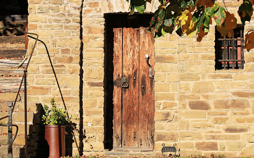 Rustic Old Wooden Door With Lion Knocker On Stone Wall