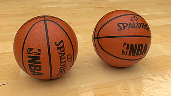 Two Spalding NBA basketballs on a light wooden floor