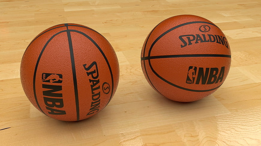 Two Spalding NBA basketballs on a light wooden floor