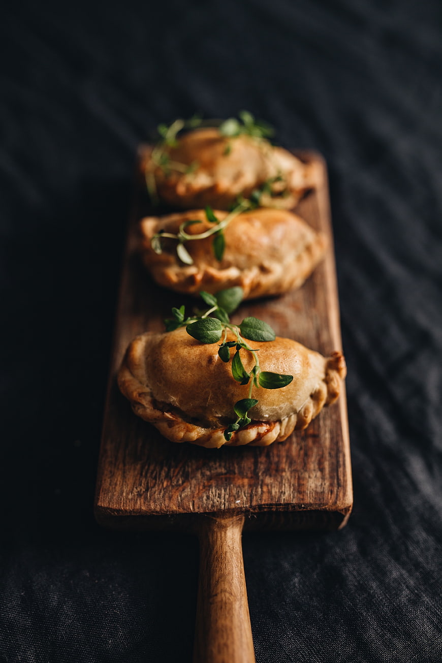 Baked Pierogi on Wooden Board with Herbs