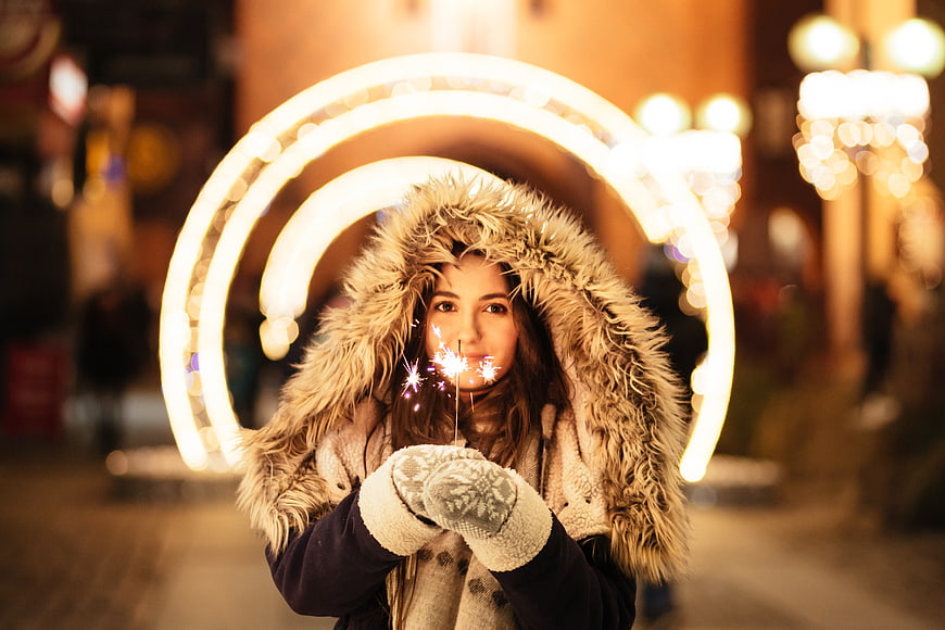 Woman with Sparkler in Winter Coat at Night