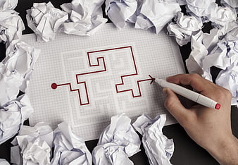 Hand drawing red solution path through maze on graph paper