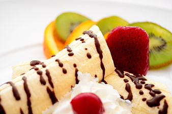 Close-up of banana dessert with chocolate drizzle and fresh fruit