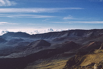 Vast volcanic crater landscape with blue sky and clouds
