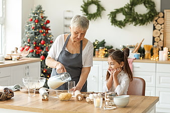 Grandmother and granddaughter baking cookies in a Christmas kitchen