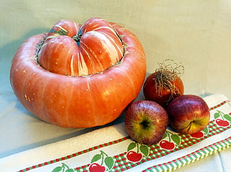 Giant striped pumpkin with apples and onion on kitchen towel