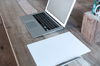 Silver laptop and blank notebook on rustic wooden desk workspace