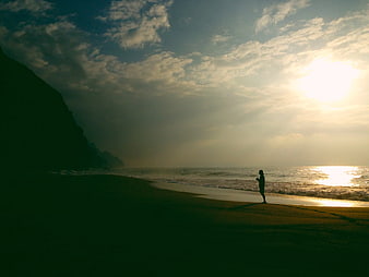 Silhouette of Person Standing on Beach at Sunset