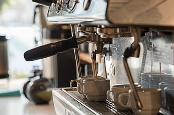 Espresso pouring from machine into ceramic cups