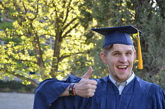 Happy Male Graduate Giving Thumbs Up in Blue Cap and Gown