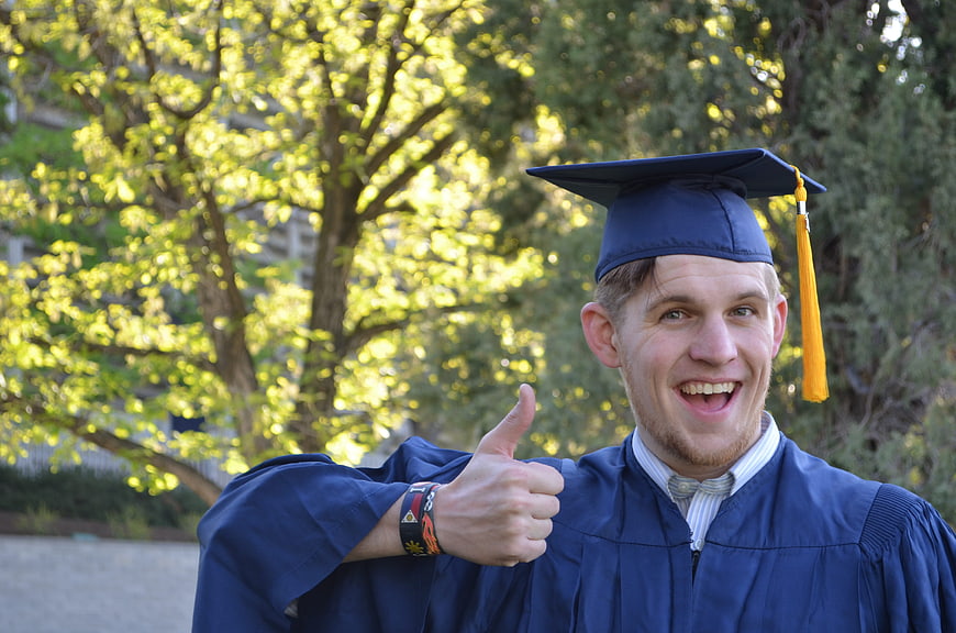 Happy Male Graduate Giving Thumbs Up in Blue Cap and Gown