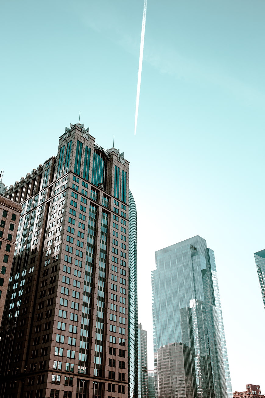 Low angle view of modern skyscrapers with contrail in sky