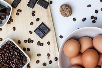 Flat lay of chocolate, coffee beans, and eggs on a wooden board
