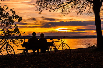 Silhouette of Couple Watching Sunset Over Lake with Bicycles