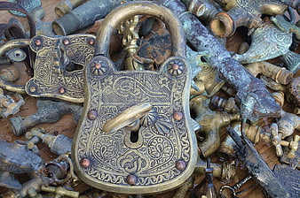 Vintage ornate brass padlock on pile of antique metal objects