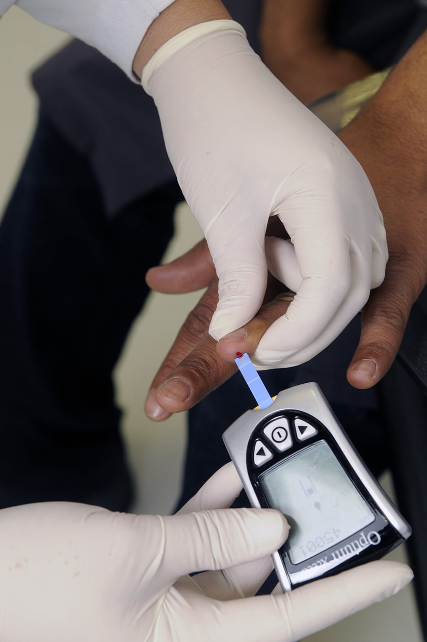 Healthcare professional performing blood glucose test on patient finger