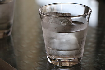 Glass of ice water on textured metal table