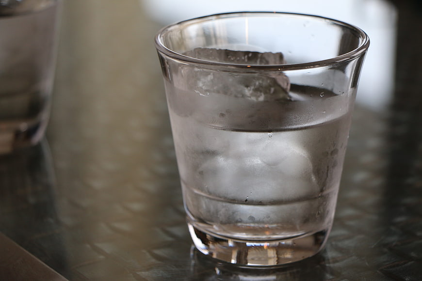 Glass of ice water on textured metal table
