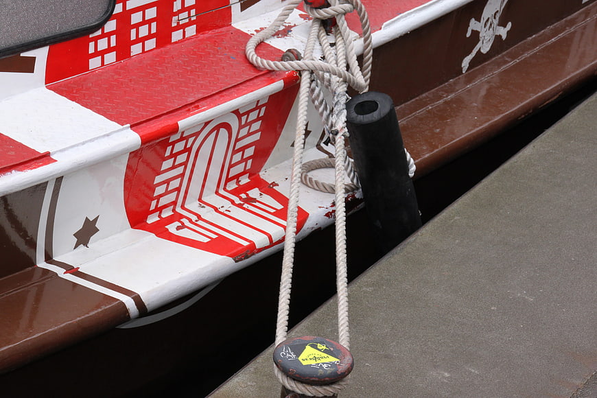 Close-up of moored boat with red and white hull details