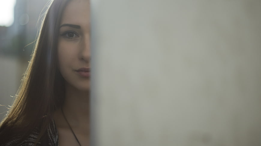 Woman Peeking from Behind Wall with Copyspace