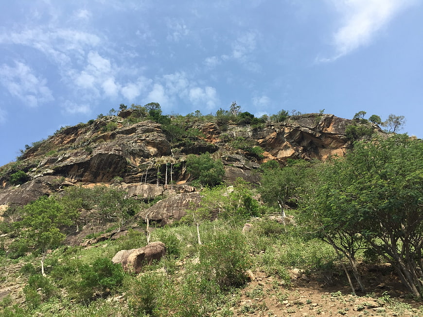 Rugged rocky hill with green vegetation under blue sky