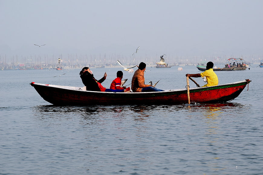 Family Feeding Seagulls on Wooden Boat in Harbor