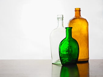 Vintage Green, Amber, and Clear Glass Bottles on Wooden Table