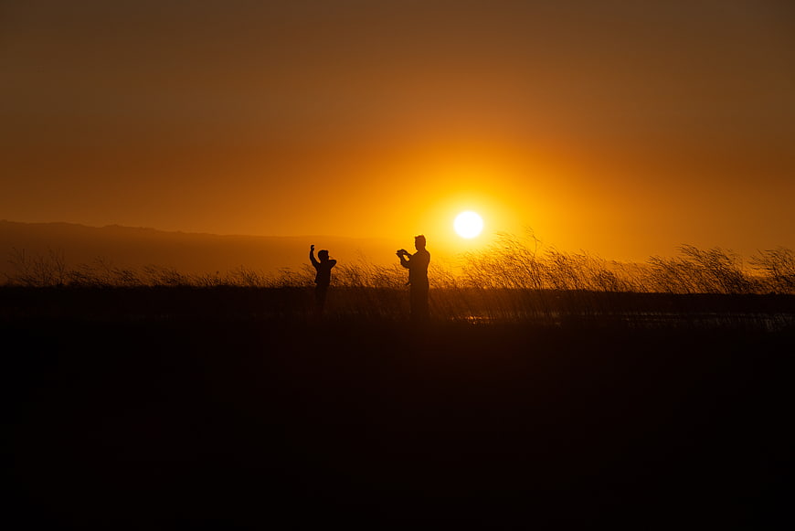 Silhouette of Parent and Child Taking Photos at Sunset
