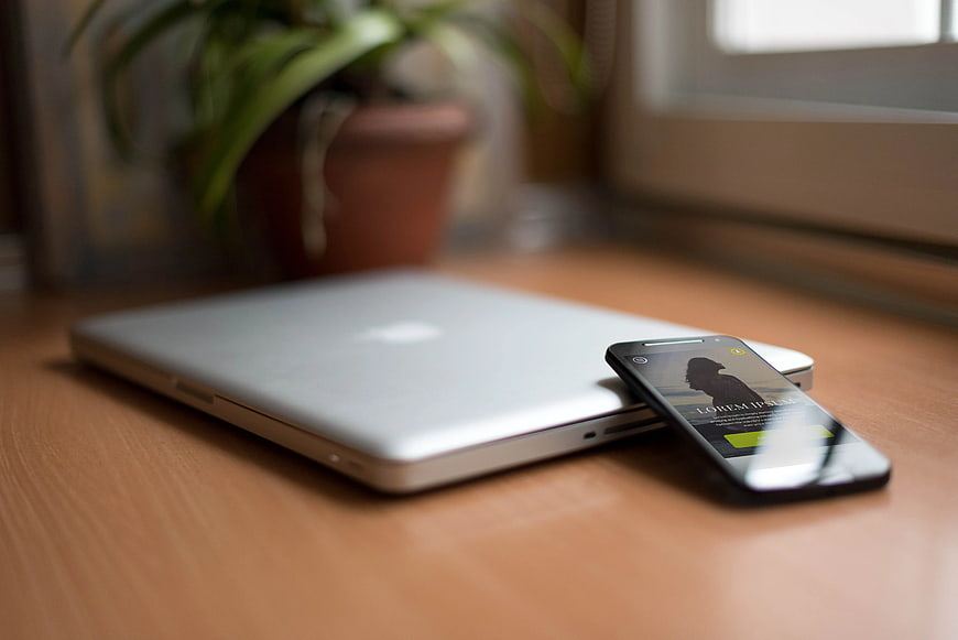 Smartphone and Laptop on Wooden Desk with Plant